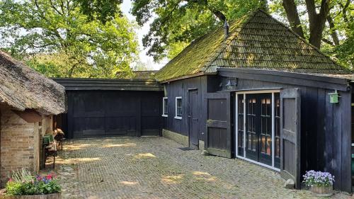 a black shed with a thatched roof at Wellness B&B Het Wapserhofje in Wapse
