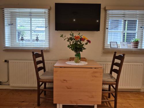 a vase of flowers sitting on a table with two chairs at Wellness B&B Het Wapserhofje in Wapse
