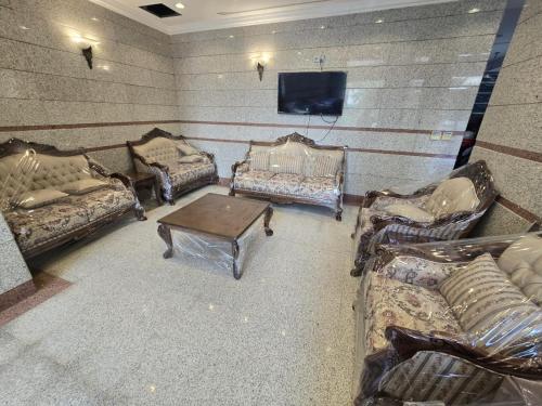 Zimmer mit Sofas, einem TV und einem Tisch in der Unterkunft فندق مهوى الفؤاد - المعابدة in An Naqāʼ