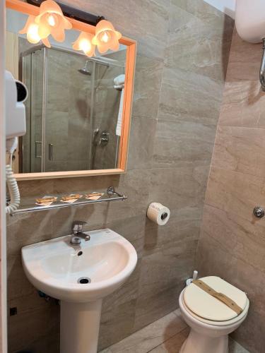 a bathroom with a sink and a toilet and a mirror at Hotel Federico II in Naples