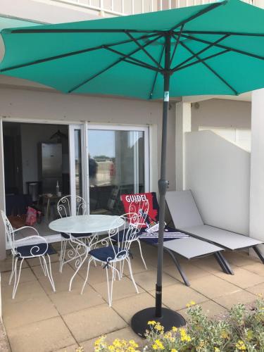 a table and chairs with a green umbrella on a patio at Maeva 7 in Guidel