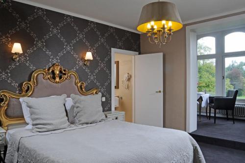 een slaapkamer met een bed met een gouden hoofdeinde bij Hotel Lodewijk Van Male in Brugge