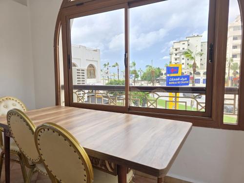 Una mesa y sillas de madera en una habitación con ventana. en Beach View Appartement, en Tánger