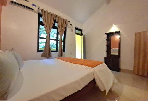 une chambre avec un grand lit blanc et une fenêtre dans l'établissement Agonda by Casa de Palmora, à Palolem