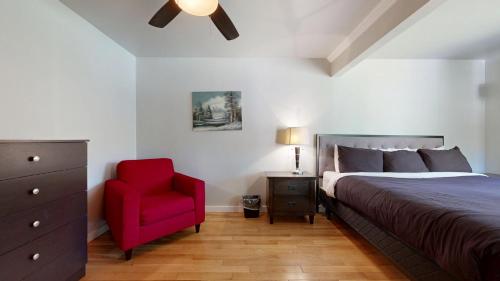 une chambre avec un lit et une chaise rouge dans l'établissement Roseway River Cottages, à Shelburne