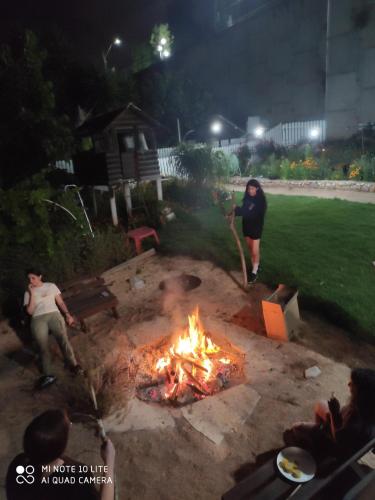 two people standing around a fire pit at night at צימר טיילת הכלנית in Ma'alot Tarshiha