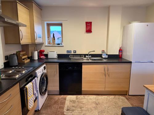 a kitchen with a white refrigerator and a dishwasher at Quirky and spacious in Lawley Bank
