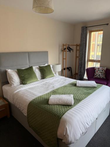 a bedroom with a large bed with green and white pillows at Quirky and spacious in Lawley Bank
