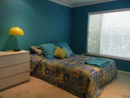 ein Schlafzimmer mit einem Bett, einer Lampe und einem Fenster in der Unterkunft A LAKEHOUSE ESCAPE - a Waterfront Reserve on shores of Lake Macquarie in Bonnells Bay