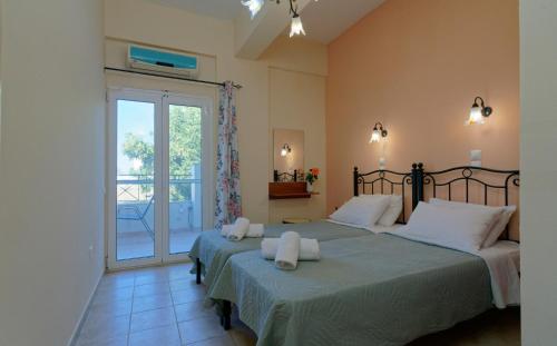 ein Schlafzimmer mit zwei Betten und einem Balkon in der Unterkunft Kamarina Apartments in Peroulades