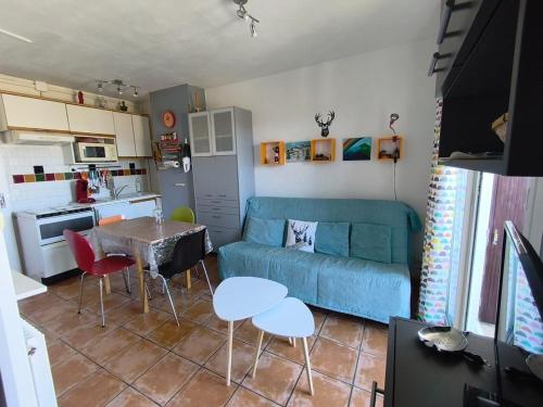 a living room with a blue couch and a table at Nid des Angles - Cœur de station vue Lac & Montagne in Les Angles