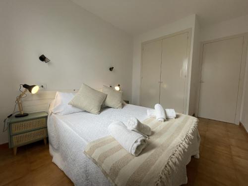 a white bedroom with two towels on a bed at Tramontana -Apartamento con piscina junto la playa in Arenal d'en Castell