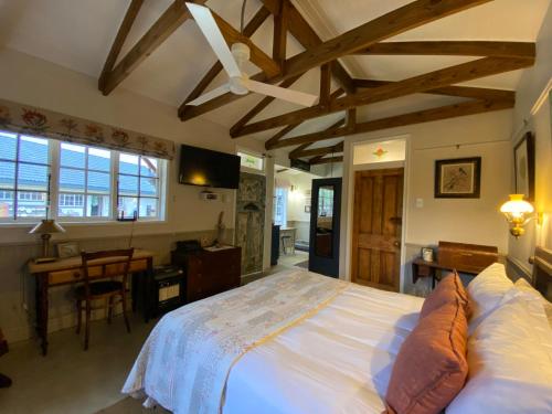 a bedroom with a large white bed and a desk at Buttercup Cottage in Nottingham Road