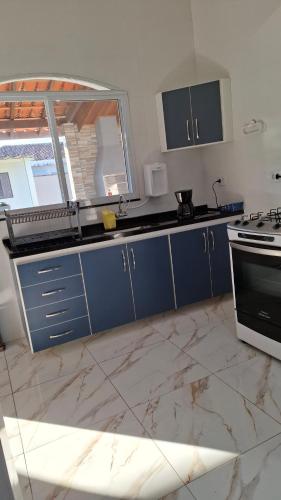 a kitchen with blue cabinets and a stove at Casa Verão Cananéia in Cananéia