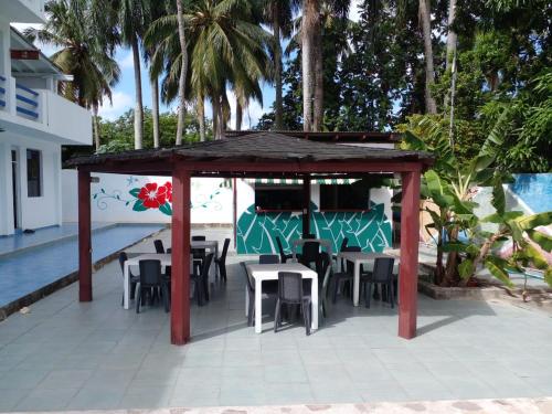 a gazebo with tables and chairs next to a pool at Apartamentos grigri in Río San Juan