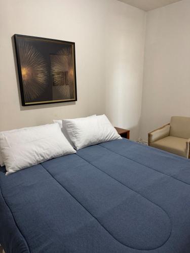 a bedroom with a blue bed and a chair at Apartamento perto do centro da Cidade in Campo Grande