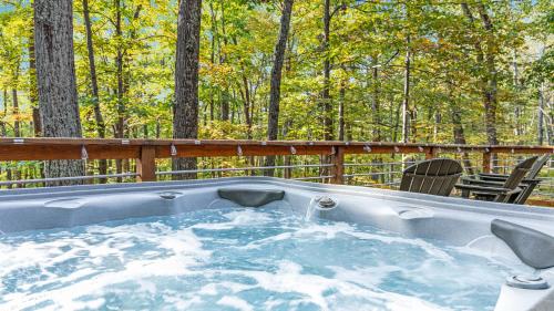 a hot tub on a deck with trees in the background at Wooded Nest, Cozy 3BR Chalet Near Spas, Downtown Berkeley Springs & Hiking in Berkeley Springs
