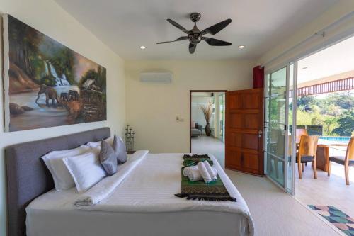 une chambre avec un lit et un ventilateur de plafond dans l'établissement Luxury Seaview Villa, Infinity Pool, Sunset, à Karon Beach