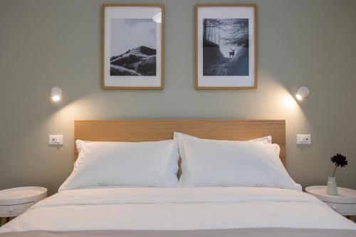 a bedroom with a white bed with three pictures on the wall at Casa Vistalago Mountain Lake Iseo Hospitality in Bossico