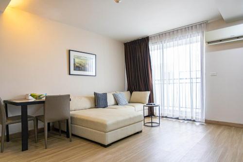 a living room with a couch and a table at Dazzle Residence ByPinny in Bangkok