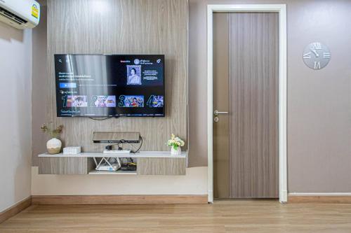 a living room with a television on a wall at Dazzle Residence ByPinny in Bangkok