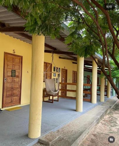 a porch of a house with columns and a chair at Recanto Monte das Oliveiras Hotel e Pousada in Tupim