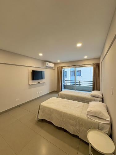 a bedroom with two beds and a tv and a window at Otero Coliving - Studio Entero U1 in San Salvador de Jujuy