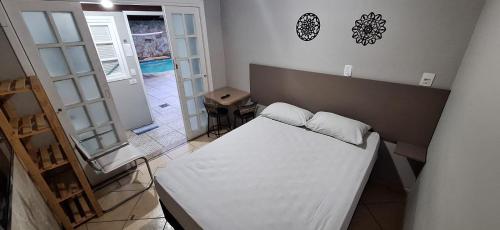 a bedroom with a white bed in a room at Bertioga litoral in Bertioga