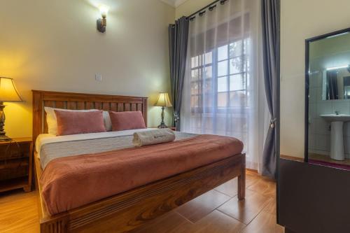 a bedroom with a large bed and a window at Riverside Suites Buwate in Kampala