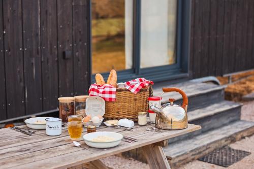 einen Picknicktisch mit einem Korb mit Speisen und Getränken in der Unterkunft Parcel Tiny House Péa au coeur de la Loire in Saint-Marcel-dʼUrfé