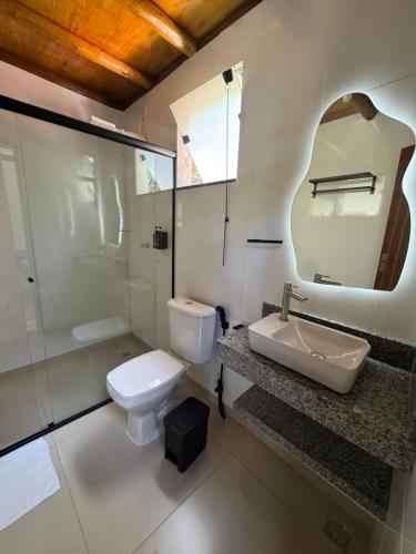 a bathroom with a toilet and a sink and a mirror at Pousada Tropical Araçatiba in Praia de Araçatiba