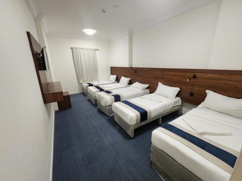 uma fileira de camas em um quarto de hotel em اصول الجوهرة العزيزية Asoul Al Jawhara Al Azizia em Al ‘Azīzīyah