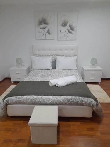 a white bedroom with a large bed with two night stands at Casinha da Palmeira in Nazaré
