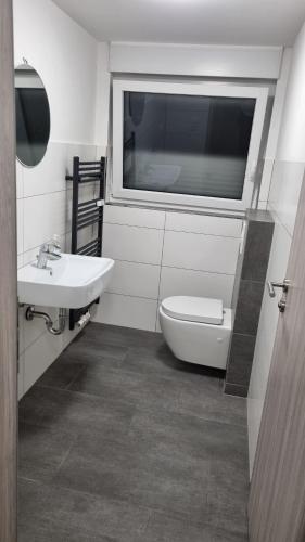 ein Badezimmer mit Waschbecken und Toilette und einem Fenster in der Unterkunft Natur Atmosphäre in Netphen