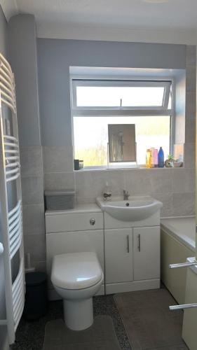a bathroom with a toilet and a sink and a window at Bnb in Abbeymead