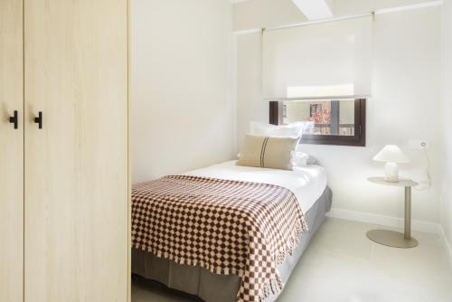 a small white bedroom with a bed and a mirror at Cima Panticosa by BeValle in Panticosa