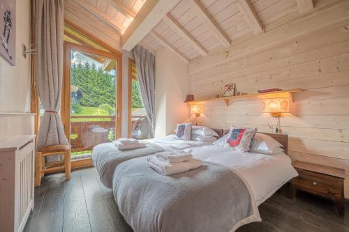 two beds in a room with a large window at Appartement Le Cerf in Les Gets