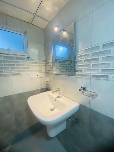 a white bathroom with a sink and a mirror at Monstera Haven Hiriketiya in Matara