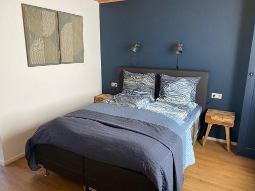 a bedroom with a bed with a blue wall at Bed en Bike Texel in Den Burg