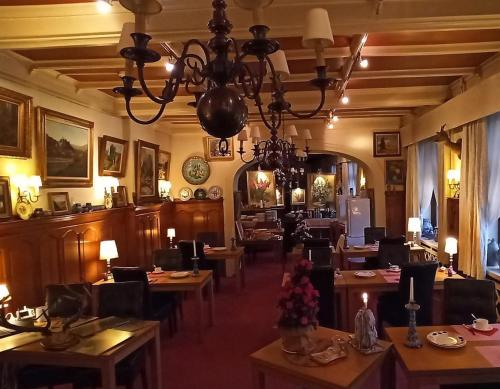 ラ・ロシュ・アン・アルデンヌにあるHotel Le Chaletのテーブルと椅子とシャンデリアのあるレストラン