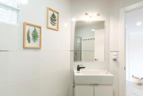een witte badkamer met een wastafel en een spiegel bij Apartamento Góndolas in Almuñécar