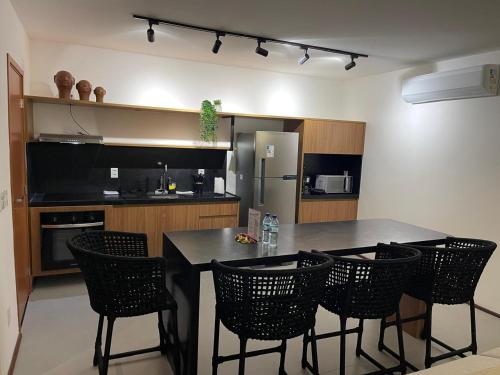 a kitchen with a table and chairs and a refrigerator at Naay Villas - Flat Beira mar exclusivo in Pôrto de Pedras