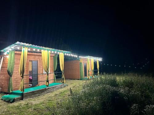 a row of wooden huts with yellow curtains and lights at Cottages Lori Berd in Lori Berd