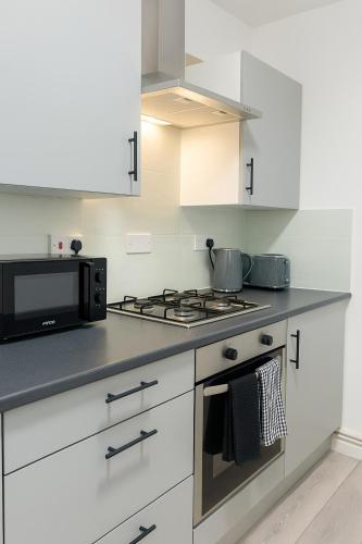 a kitchen with a stove and a microwave at Quiet & Modern 3-Bed Home Near Beach & Marina in Hartlepool