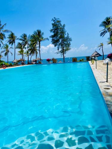 a swimming pool on the beach with palm trees at Nautical Nest Beachfront Apartments in Malindi