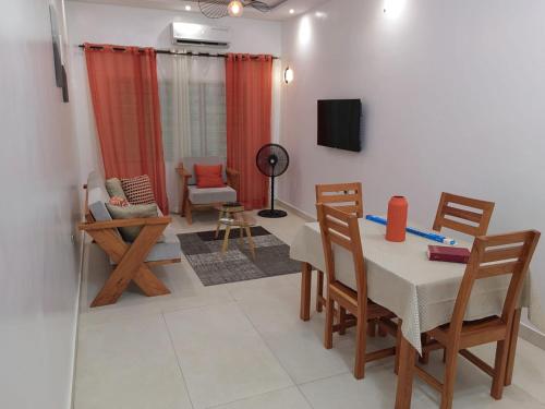 un salon avec une table, des chaises et une télévision dans l'établissement Magnifique Appartement 2 chambres Salon, à Cotonou