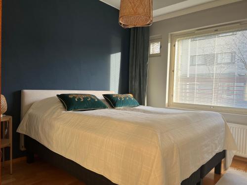 ein Schlafzimmer mit einem Bett mit zwei Kissen und einem Fenster in der Unterkunft Kaksio järvinäkymällä ja saunalla Lahden Satamasta in Lahti