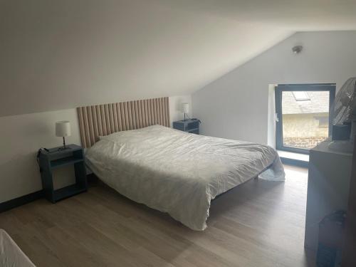 ein Schlafzimmer mit einem Bett, zwei Tischen und einem Fenster in der Unterkunft Le petit four à pain in Iffendic