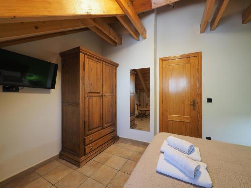 1 dormitorio con TV y 1 cama con toallas en Apartamentos Fogaron, en Saravillo