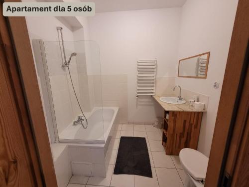 a white bathroom with a tub and a sink at Forum Sopot in Sopot